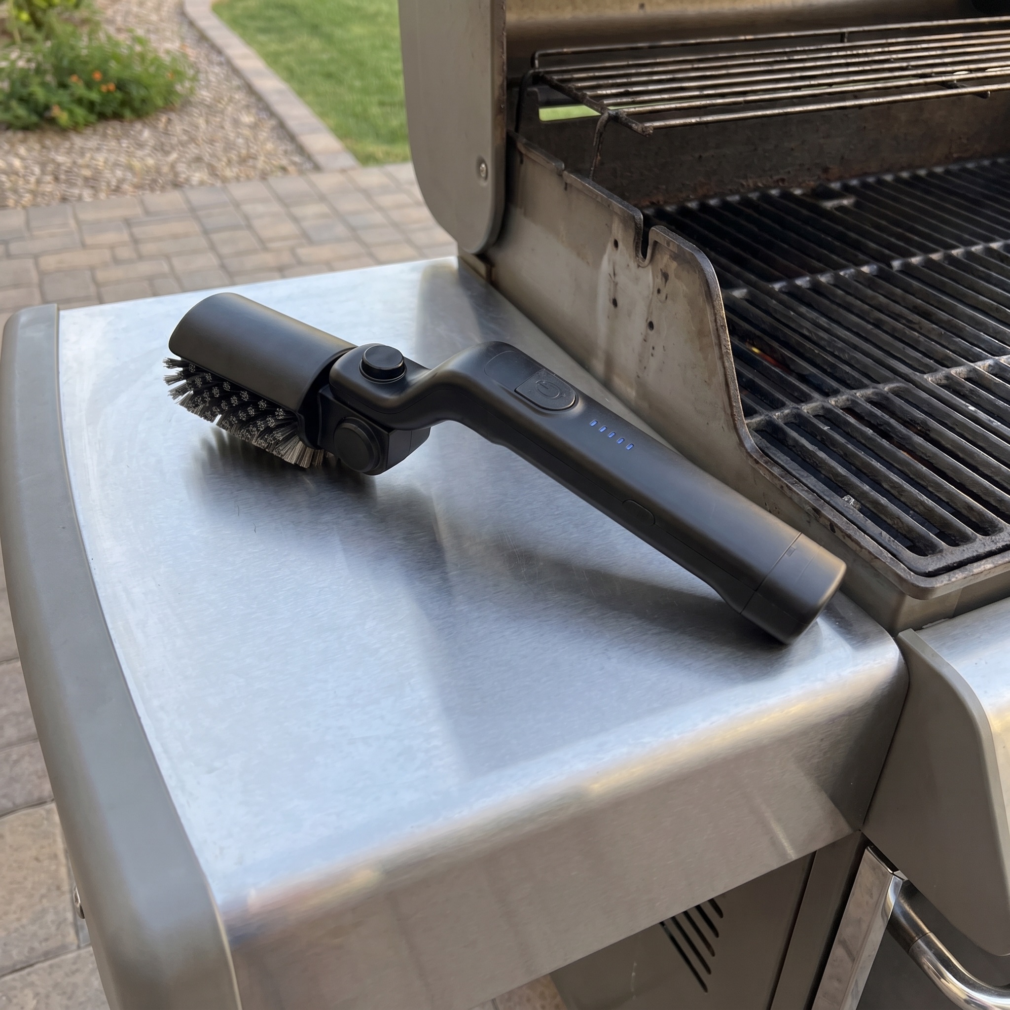 The brush hanging on a hook beside the grill on its USB-C charging stand